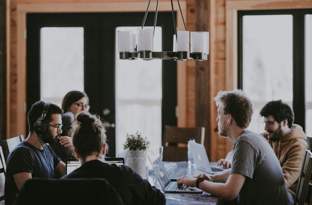 Group of people working around a long table on laptops